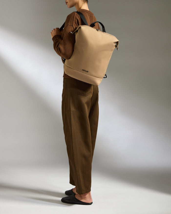 a woman wearing brown pants and a brown backpack