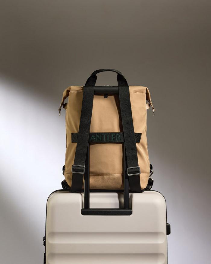 a tan backpack on top of a white suitcase