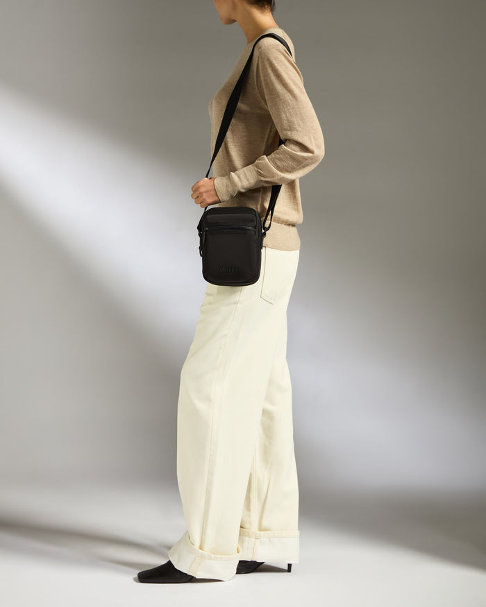 a woman wearing a brown sweater and white pants
