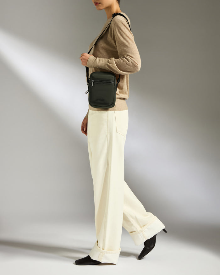 a woman in a brown sweater and white pants