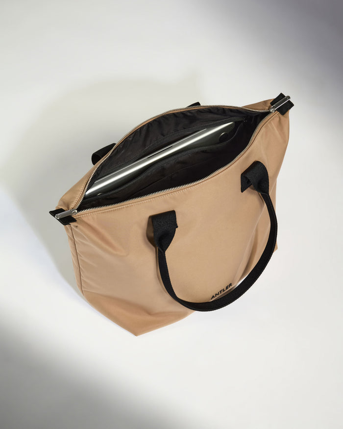 a tan bag with black handles