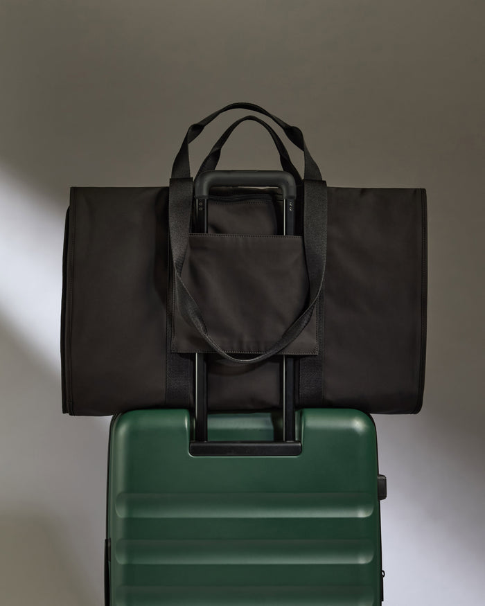 a black bag on top of a green suitcase