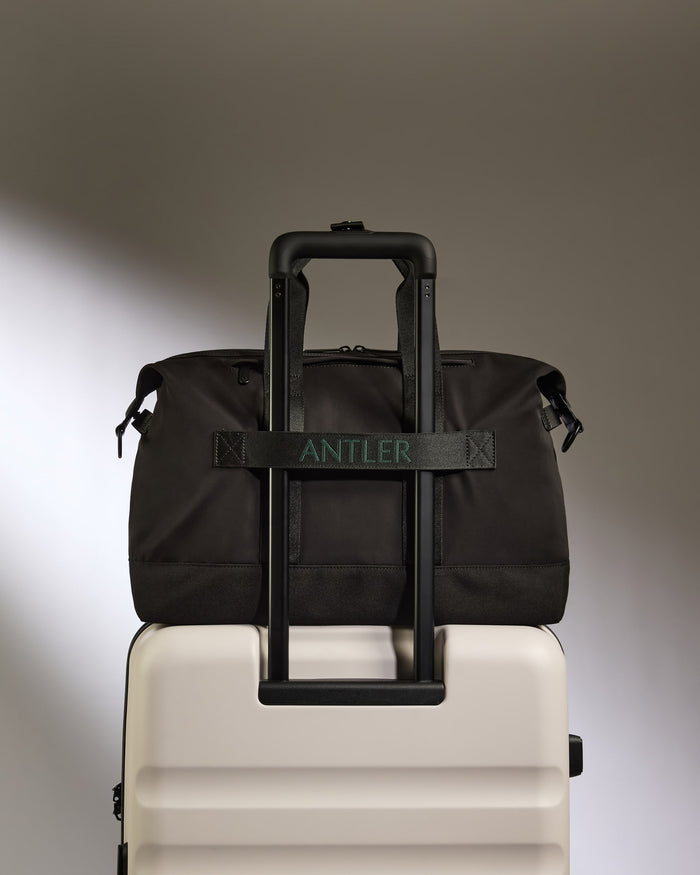 a black bag on top of a white suitcase