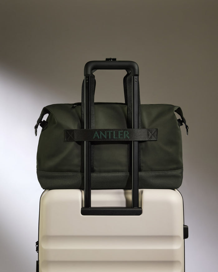 a green bag on top of a white suitcase