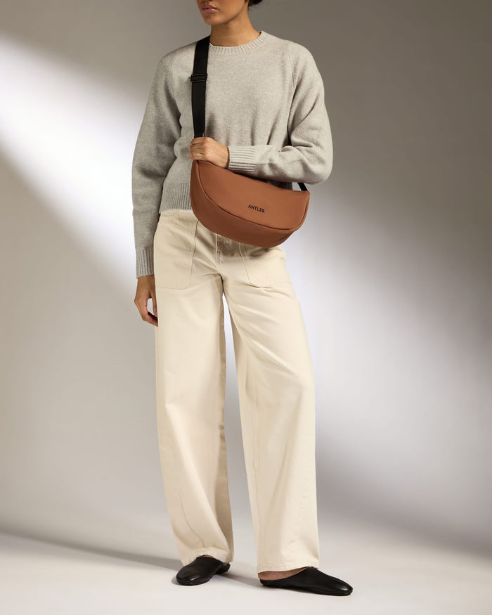 a woman wearing a grey sweater and white pants