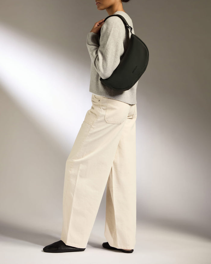 a woman in a grey sweater and white pants