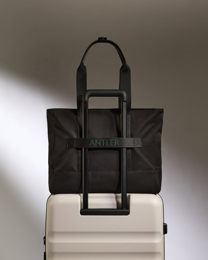 a black bag on top of a white suitcase