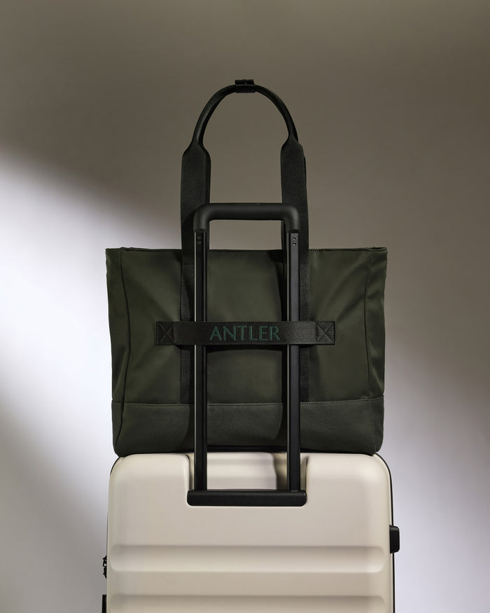 a green bag on top of a white suitcase