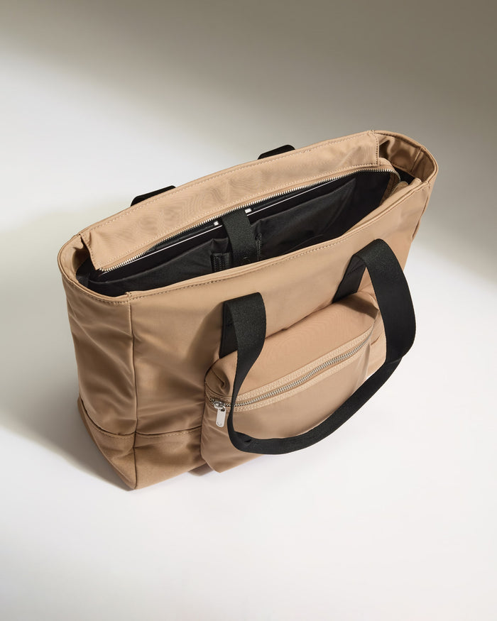 a tan bag with black handles