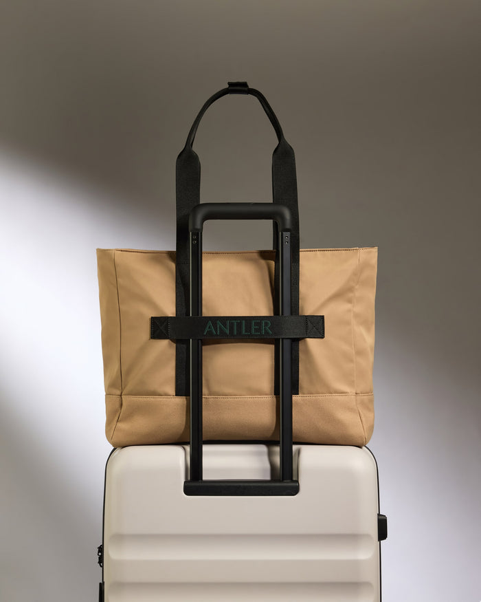 a tan bag on top of a white suitcase