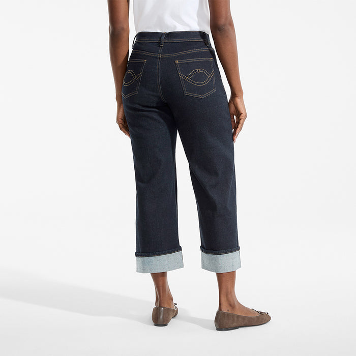 Person wearing dark blue jeans with rolled-up cuffs on a white background