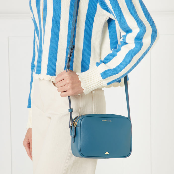 A woman in a blue and white striped sweater holds a teal Lulu Guinness crossbody bag.