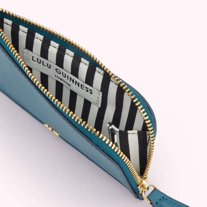 Teal Lulu Guinness zip-around purse open to reveal black and white striped interior.
