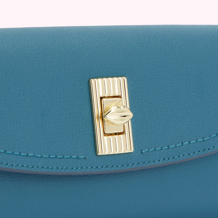 Close-up of a teal leather wallet with a gold lip-shaped clasp.