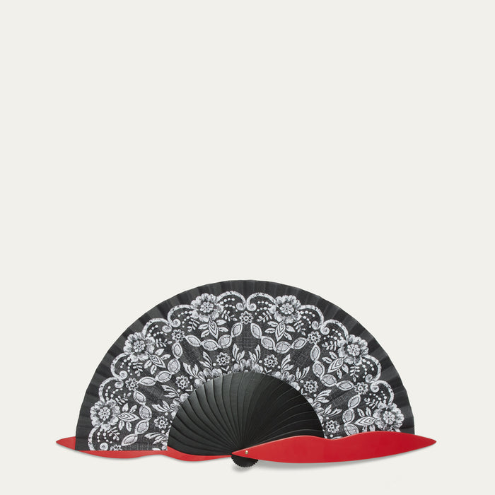 Black handheld fan with white floral lace patterns and red accents on a light gray background
