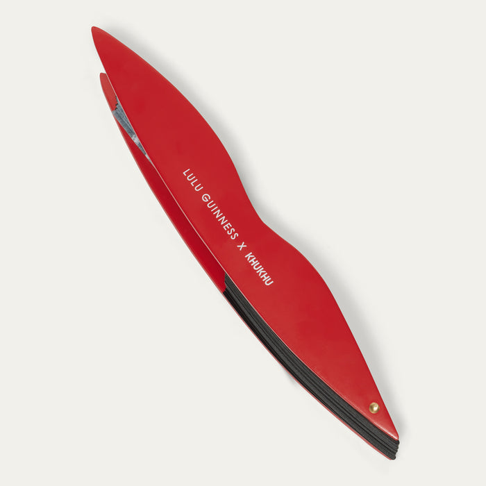 Detail of red handheld fan closed with 'Lulu Guinness x Khukhu' branding on a white background