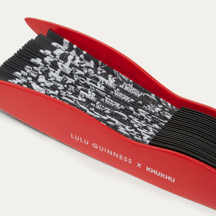 Close-up detail image of a red  handheld fan featuring 'Lulu Guinness x Khukhu' branding on a white background