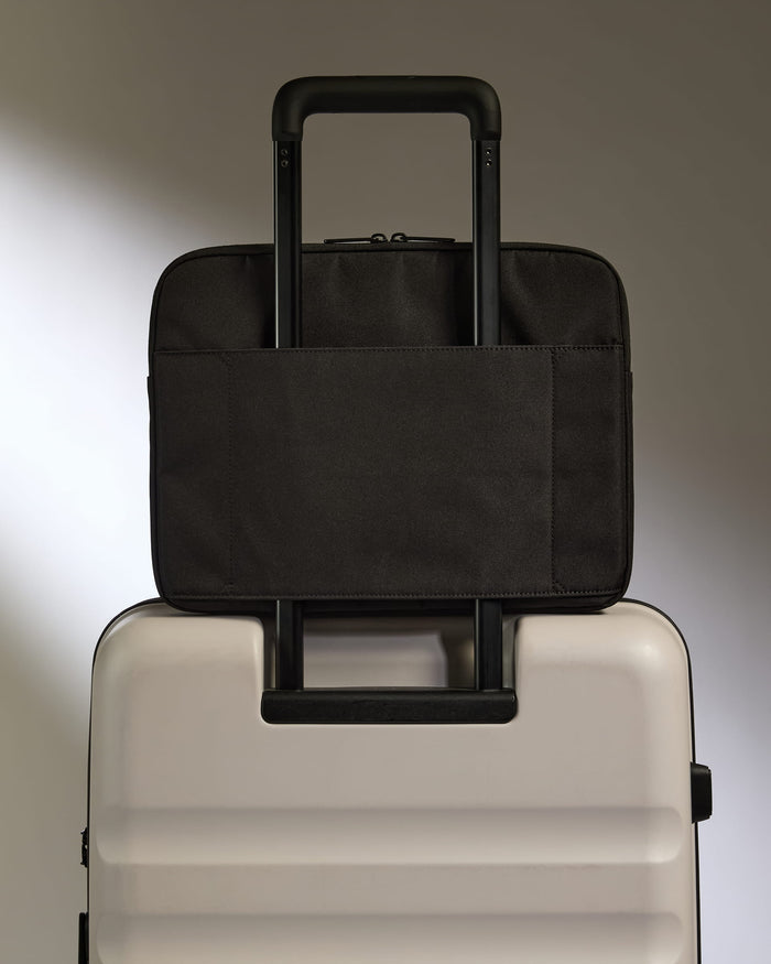 a black bag on top of a white suitcase
