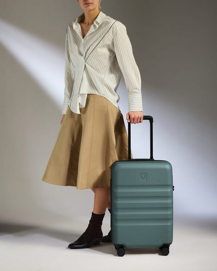 a woman in a skirt and a white shirt holding a suitcase