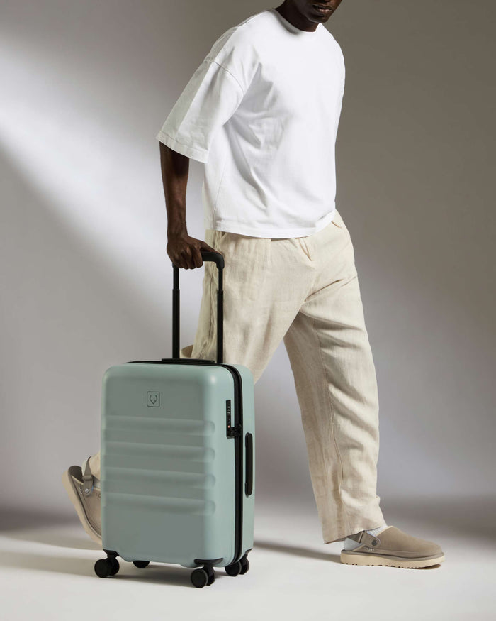 a man in white shirt and beige pants holding a suitcase