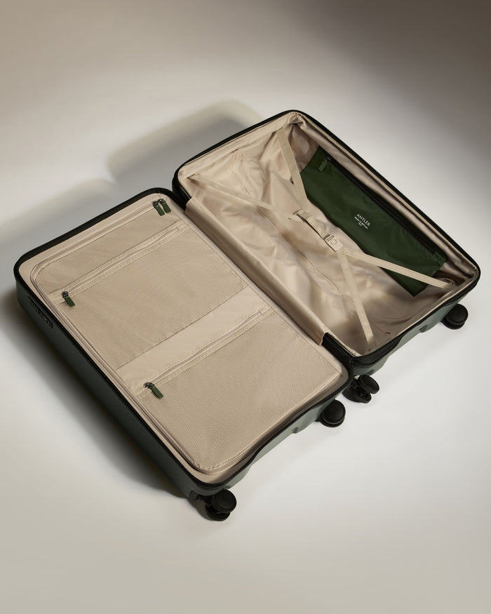 a suitcase with wheels and a green bag