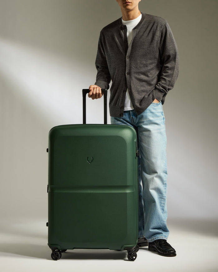 a man standing next to a green suitcase