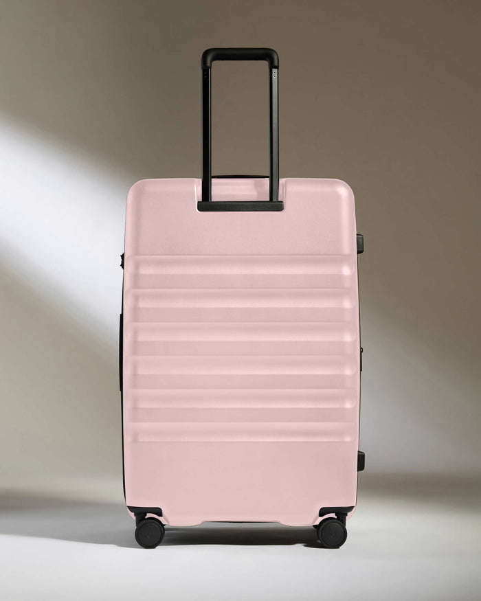 a pink suitcase with black wheels