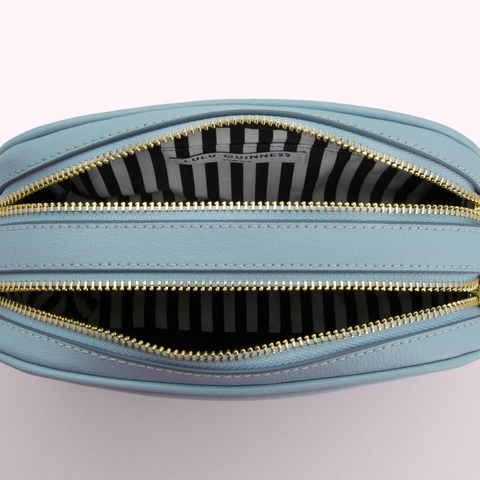 Open light blue Lulu Guinness crossbody bag showing black and white striped interior lining.