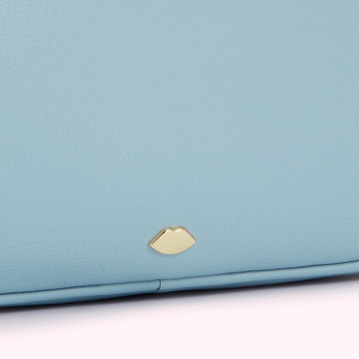 Close-up of a light blue leather purse with a gold lip-shaped emblem.