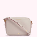 A light beige Lulu Guinness crossbody bag with a pink strap.