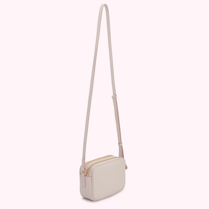 Light beige rectangular crossbody bag with a long strap and gold zippers.