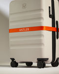 a white suitcase with orange ribbon