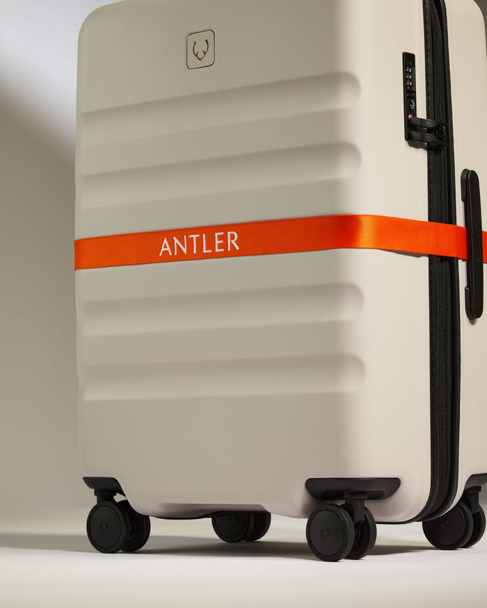 a white suitcase with orange ribbon