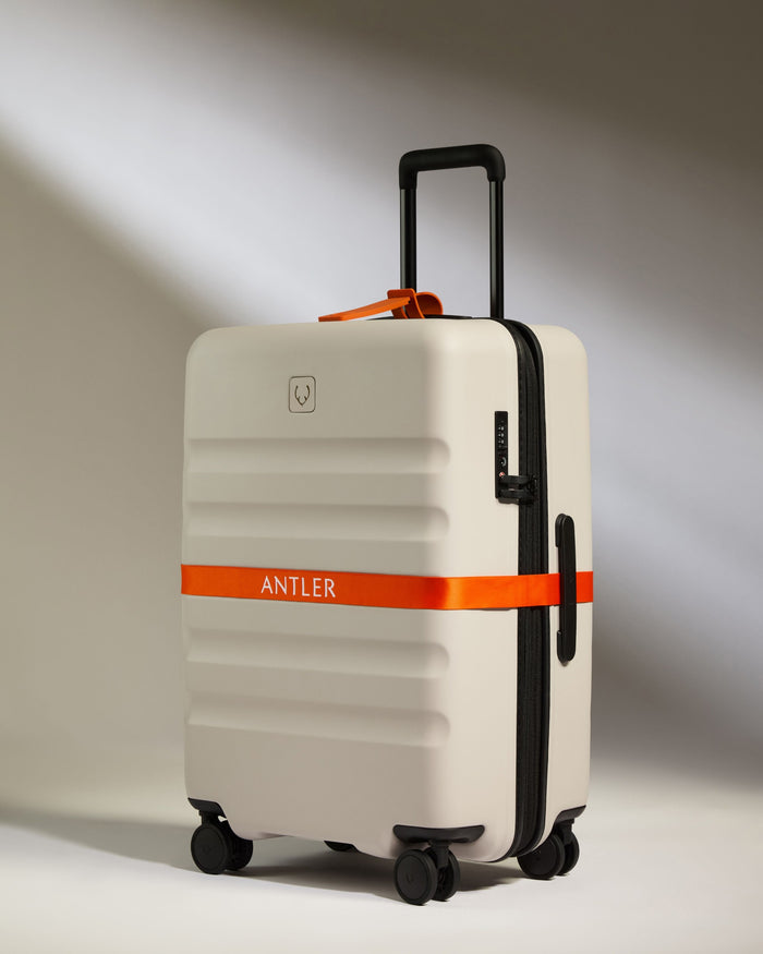 a white suitcase with orange ribbon