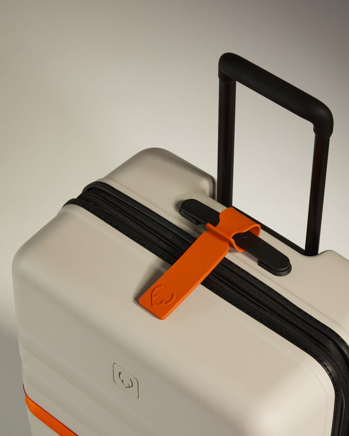 a white suitcase with a orange tag on it