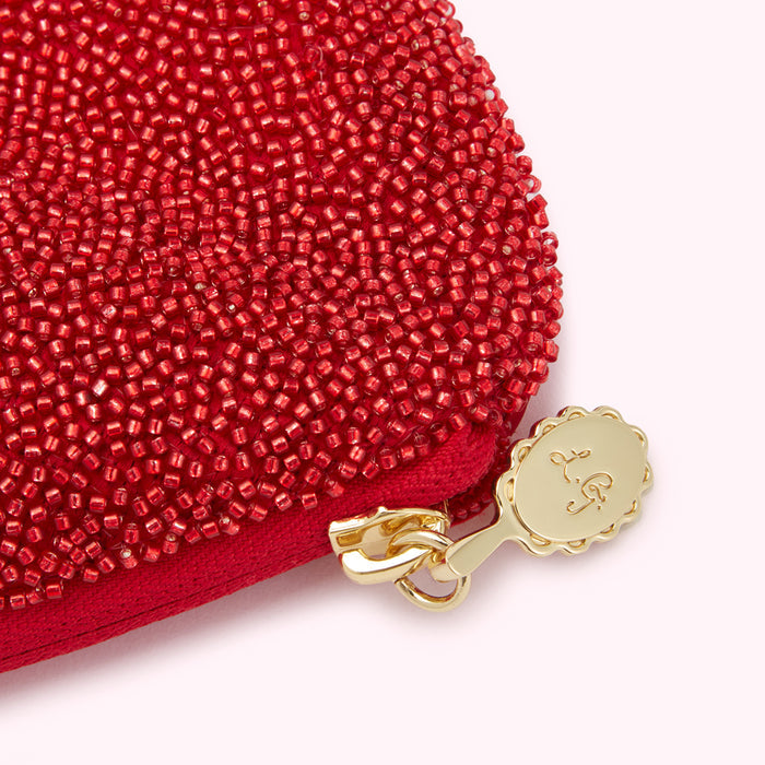 Close-up of a red beaded purse with a gold clasp and logo.