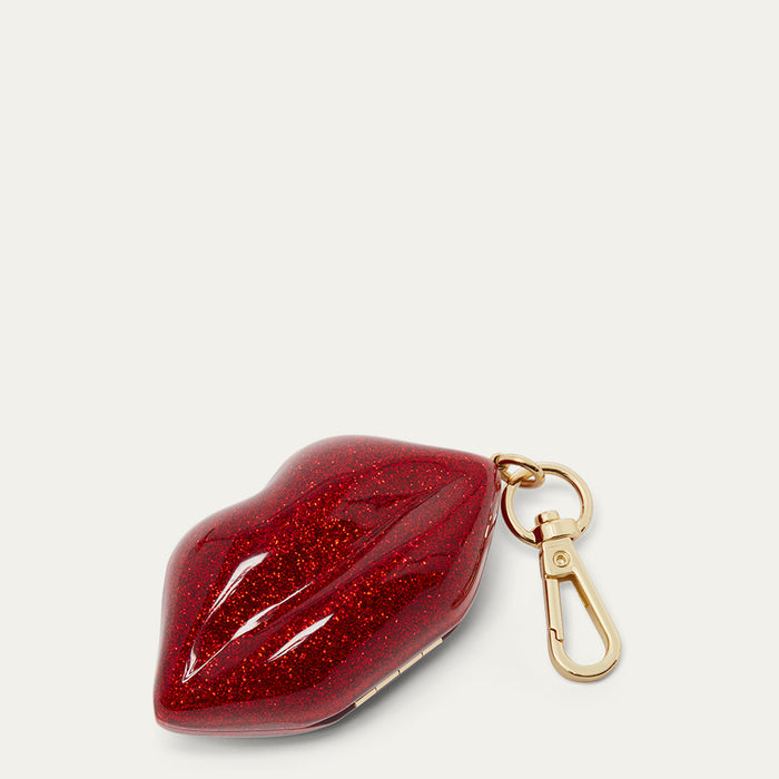 Red glittery lip-shaped keychain with a gold clasp on a light gray background