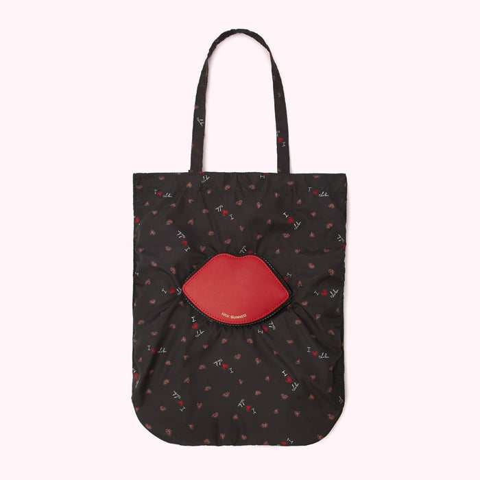 Black tote bag with red lips pattern and a large red lip-shaped pocket.