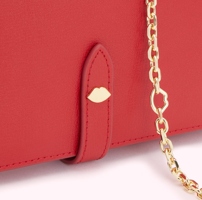 Close-up of a red leather wallet with a gold chain and lip-shaped detail.