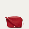 Red handbag with gold accents on a light beige background