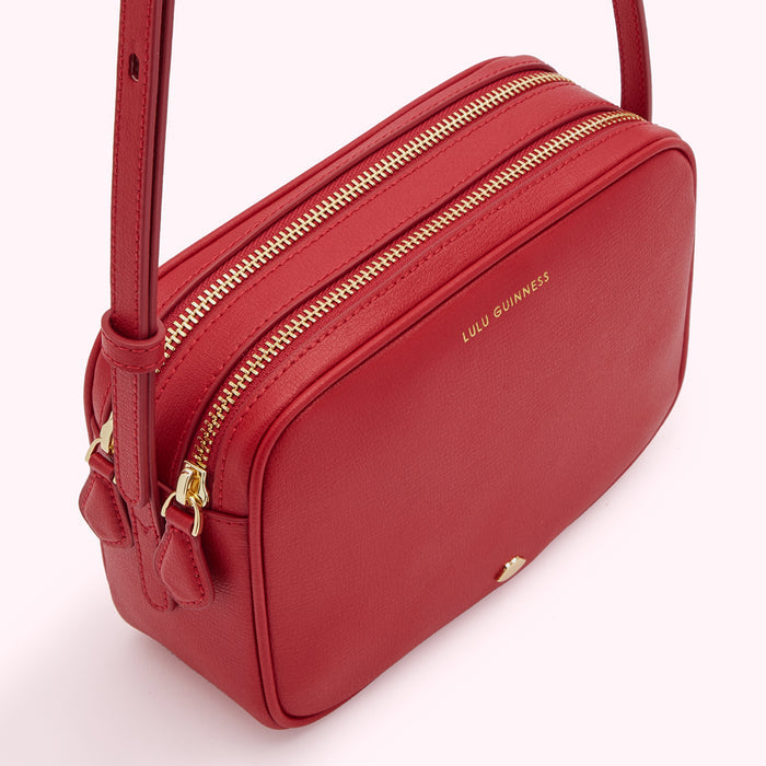 Red Lulu Guinness crossbody bag with gold zippers.