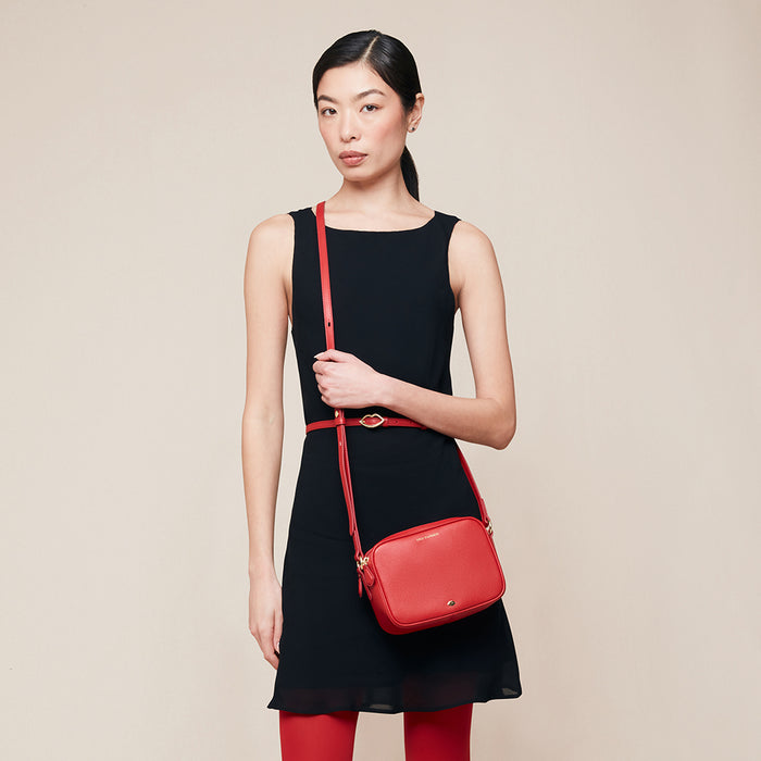 Woman holding a red handbag against a beige background