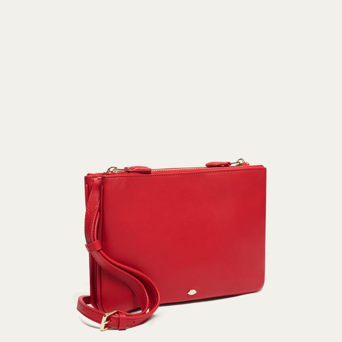 Red crossbody bag with a strap on a light beige background