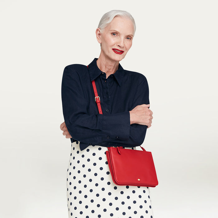 Woman holding a red handbag against a plain background