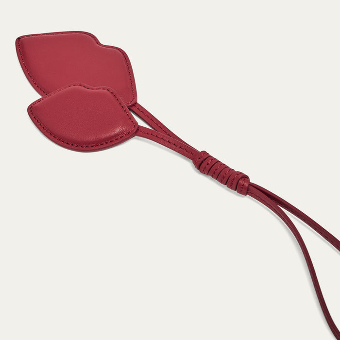 Red leather lip shaped charm on a light grey background