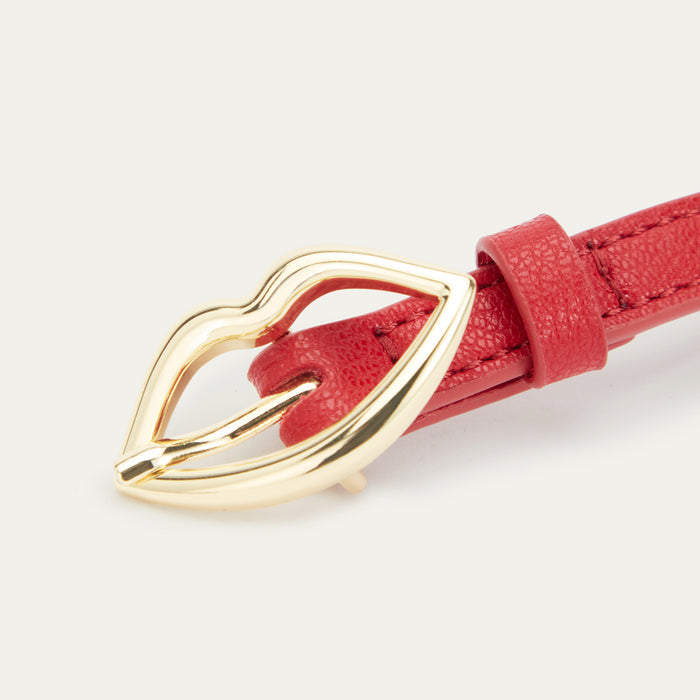 Close up image of a gold lip shaped buckle on a red leather belt.