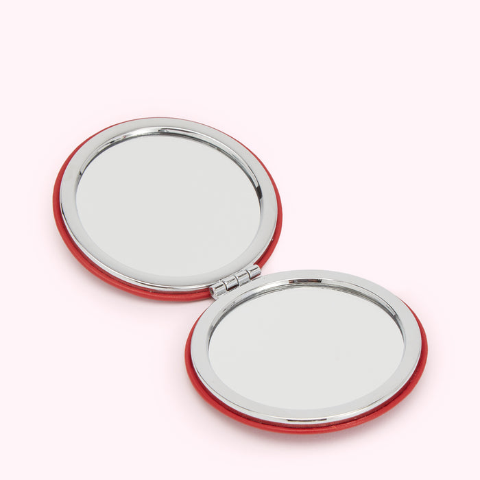 Red compact mirror open to show two circular mirrors.