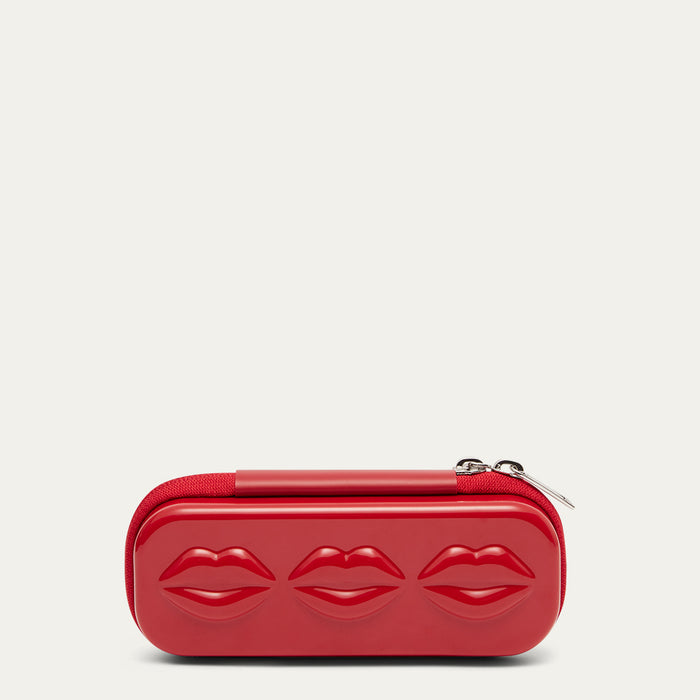 Red sunglasses case with lip details and silver zip pulls on a beige background.