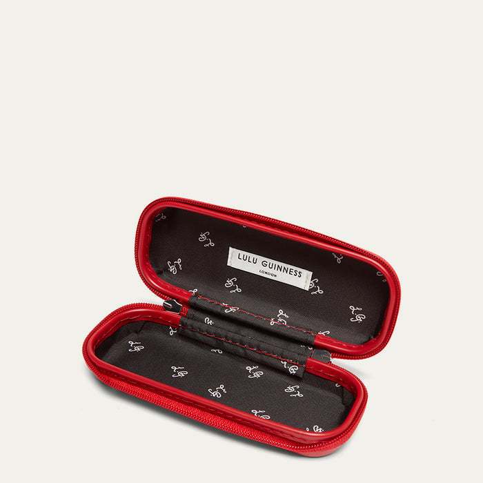 Red and black sunglasses case open with Lulu Guinness branding on a light gray background