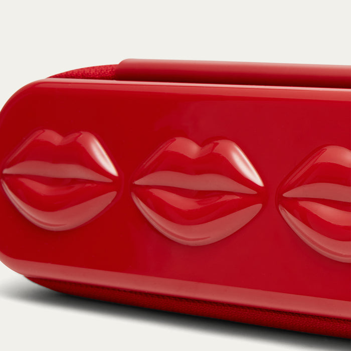 Close-up of a red sunglasses case with lip design on a white background